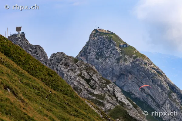 View of the rock formations at the summit of Mount Pilatus with a paraglider flying by