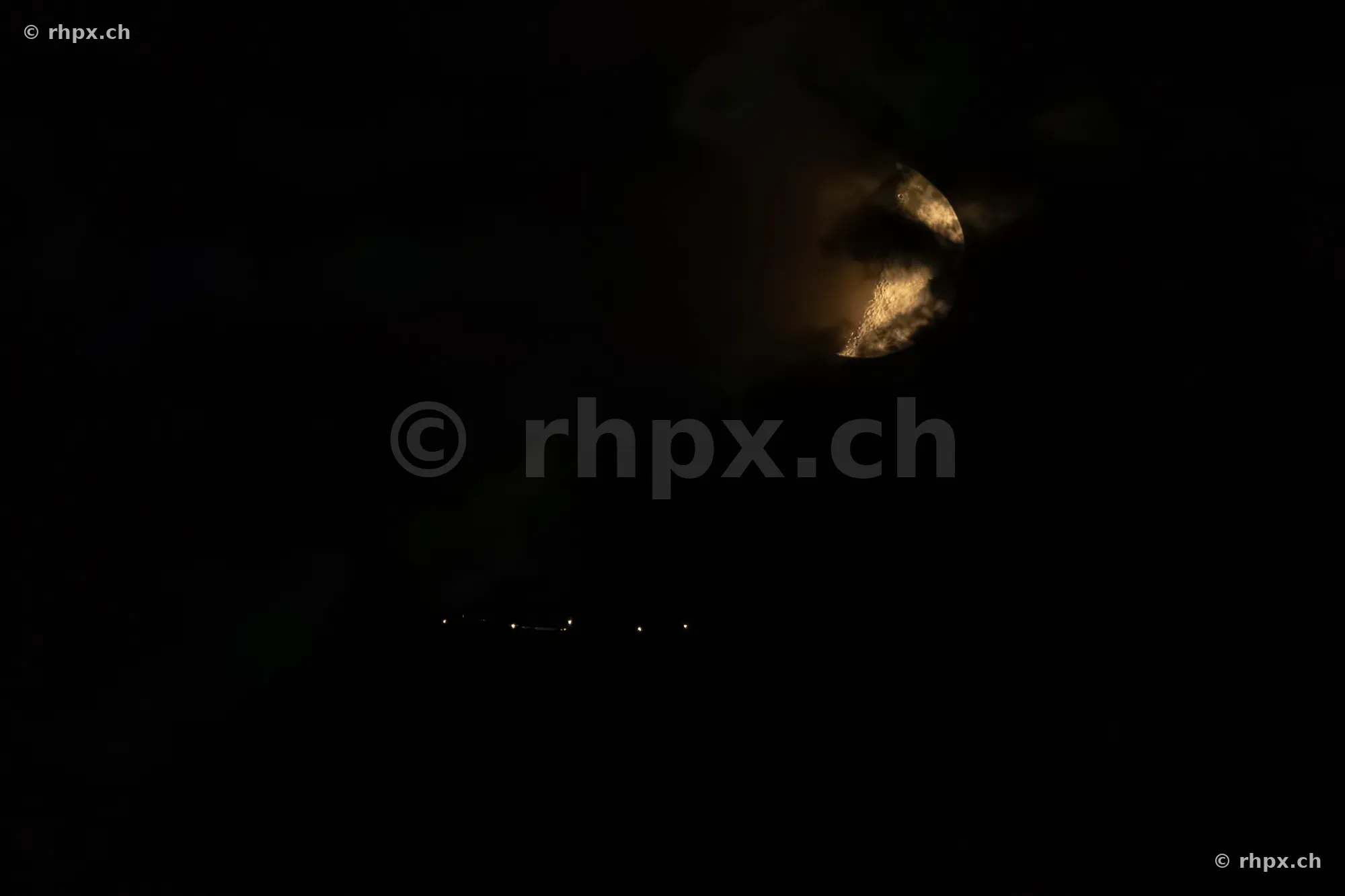 Der Mond scheint in der Nacht durch Wolken über dem Pilatusmassiv.