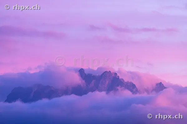 Der in Wolken gehüllte Gipfel des Pilatus bei violettem Licht in der Abenddämmerung.