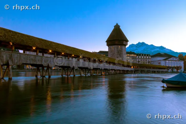 Die beleuchtete Kapellbrücke mit Wasserturm in Luzern in der Dämmerung