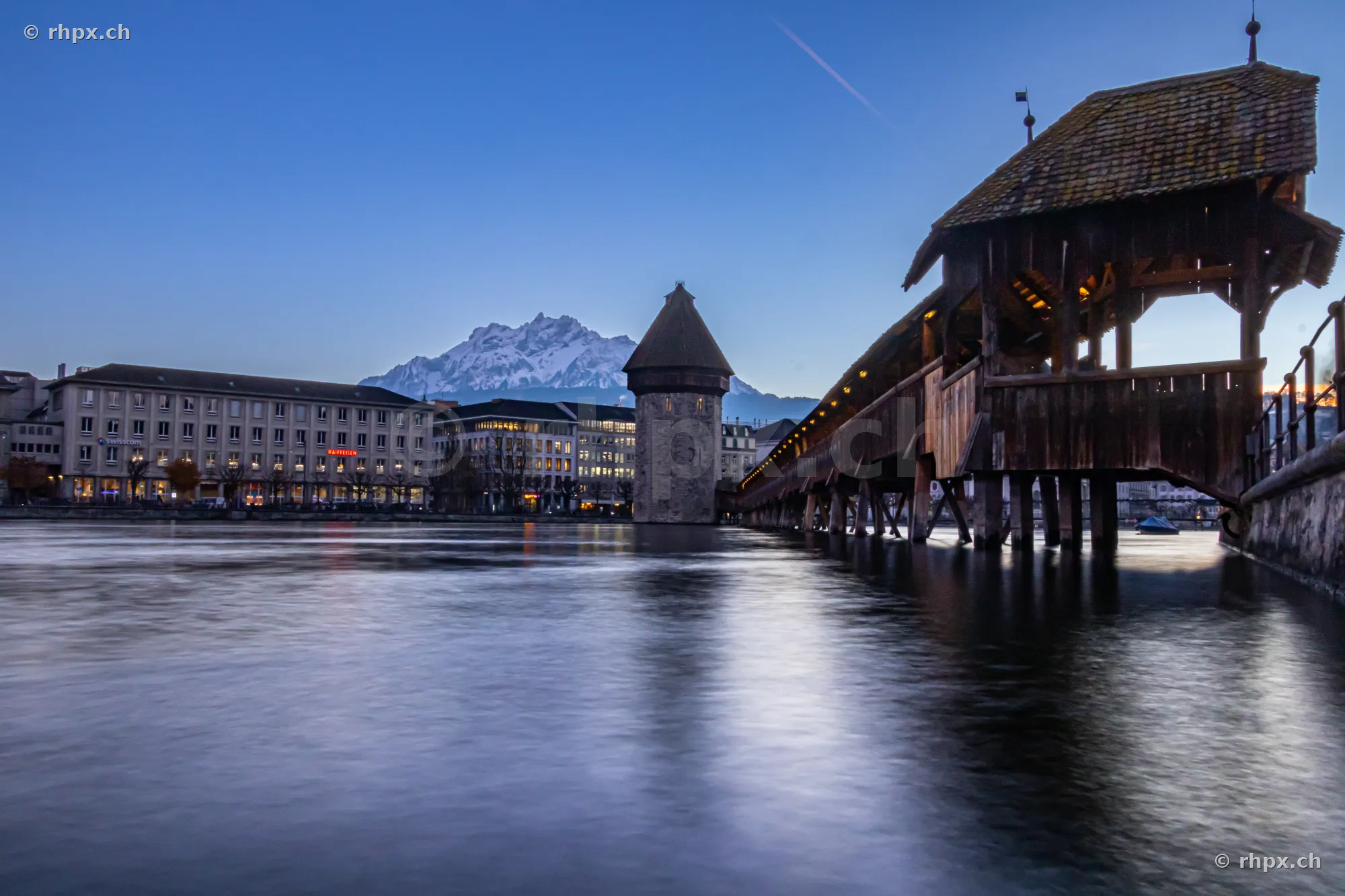 View of the Chapel Bridge and Wasserturm in Lucerne with Mount Pilatus in the background during the blue hour