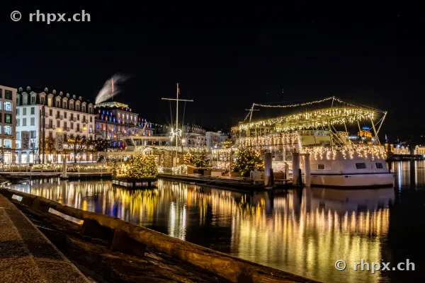 A Christmas-lit passenger boat moored at the Lucerne quay at night.
