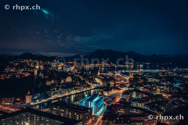 Nächtlicher Blick auf die weihnachtlich beleuchtete Stadt Luzern mit dem Vierwaldstättersee und den Bergen im Hintergrund