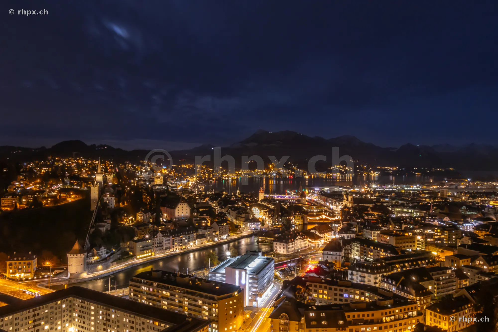 Night view from above of the illuminated city of Lucerne during Christmas time with the Reuss river