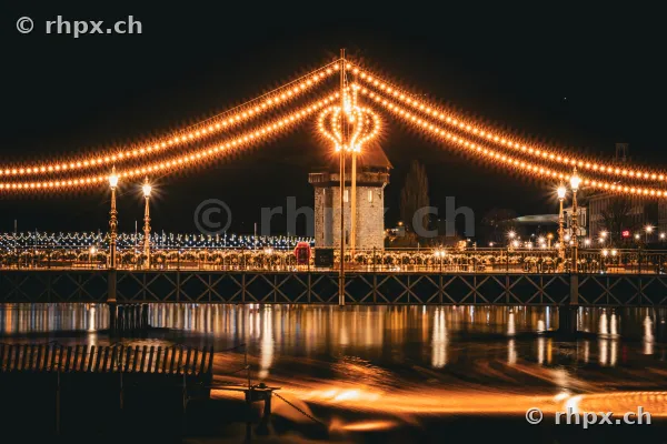 Weihnachtlich beleuchtete Seebrücke in Luzern bei Nacht mit dem Wasserturm im Hintergrund