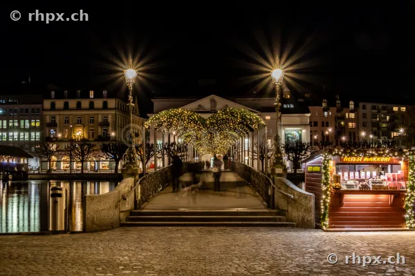 Festlich beleuchteter Zugang zur Jesuitenkirche in Luzern bei Nacht mit einem Marktstand