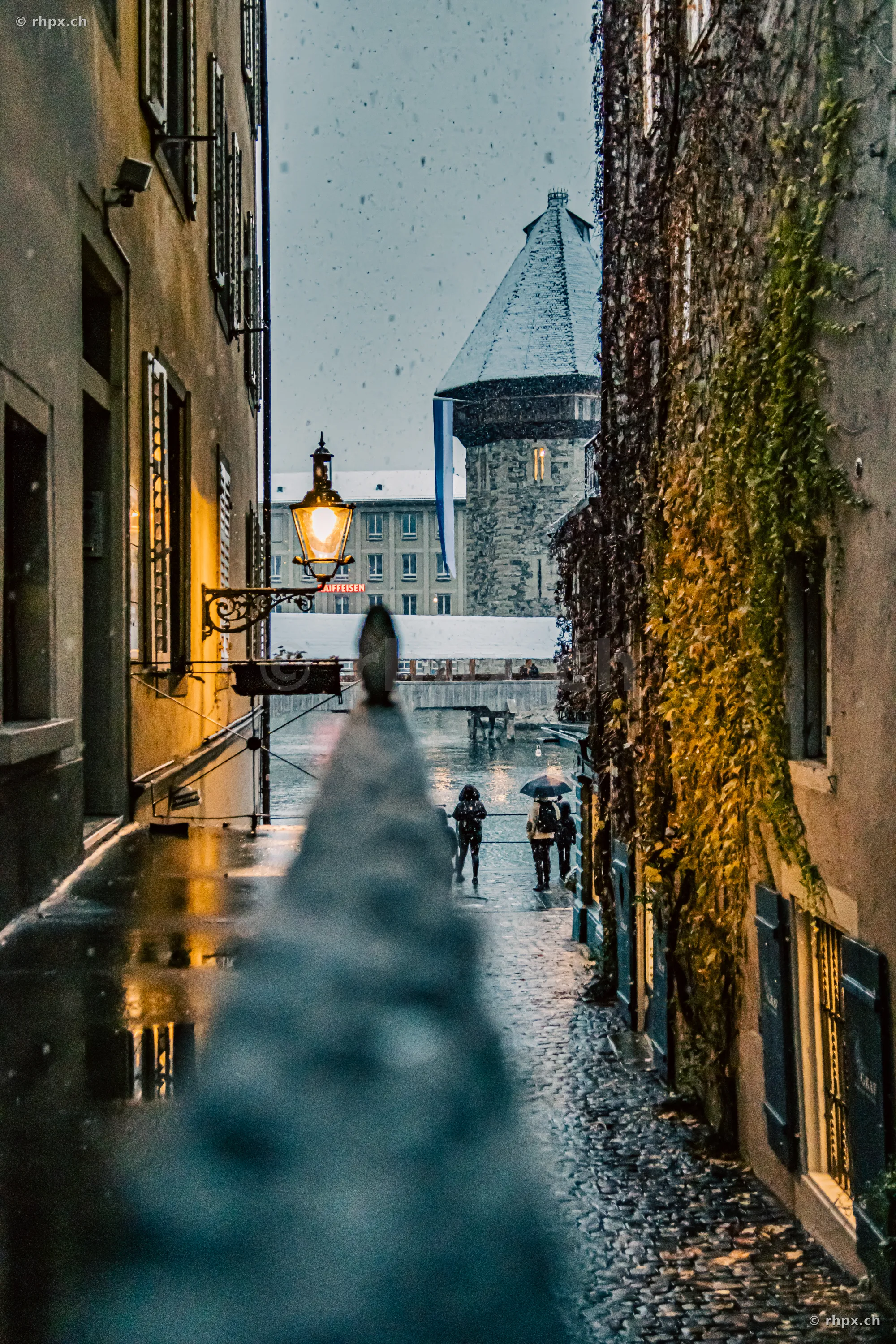 View through an alley towards the snow-covered Wasserturm in Lucerne during a light snowfall