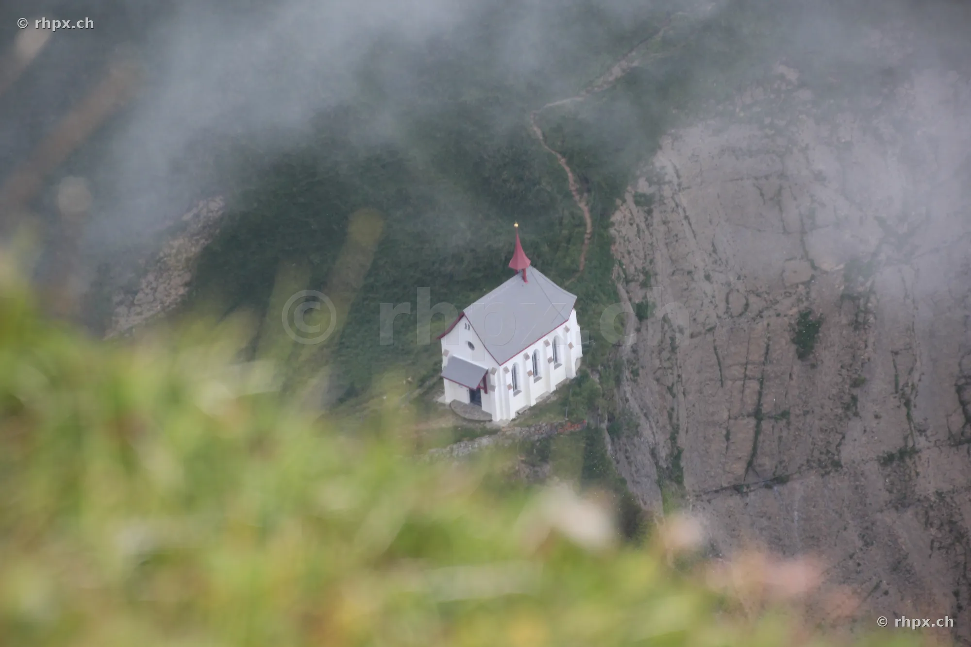 Die Pilatuskapelle eingebettet in Felswände und Nebel von oben betrachtet