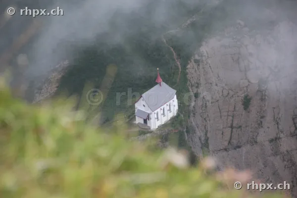 The Pilatus chapel nestled in rock walls and fog seen from above