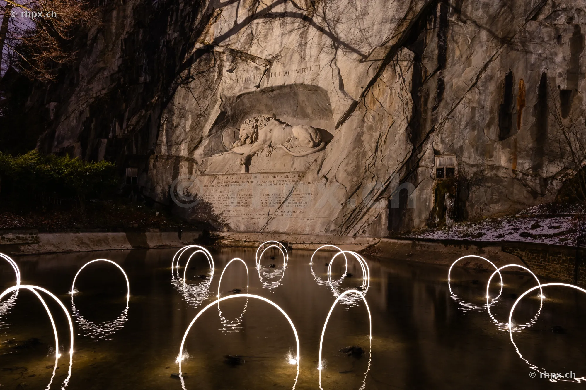 Das Löwendenkmal in Luzern bei Nacht, illuminiert durch Lichtinstallationen des Lilu Lichtfestivals im Wasserbecken.