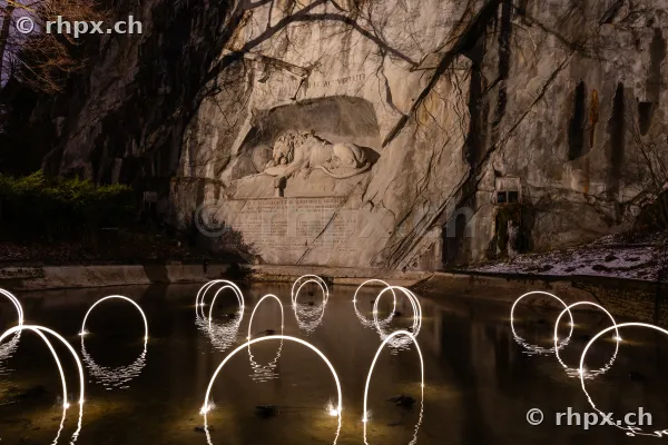Das Löwendenkmal in Luzern bei Nacht, illuminiert durch Lichtinstallationen des Lilu Lichtfestivals im Wasserbecken.