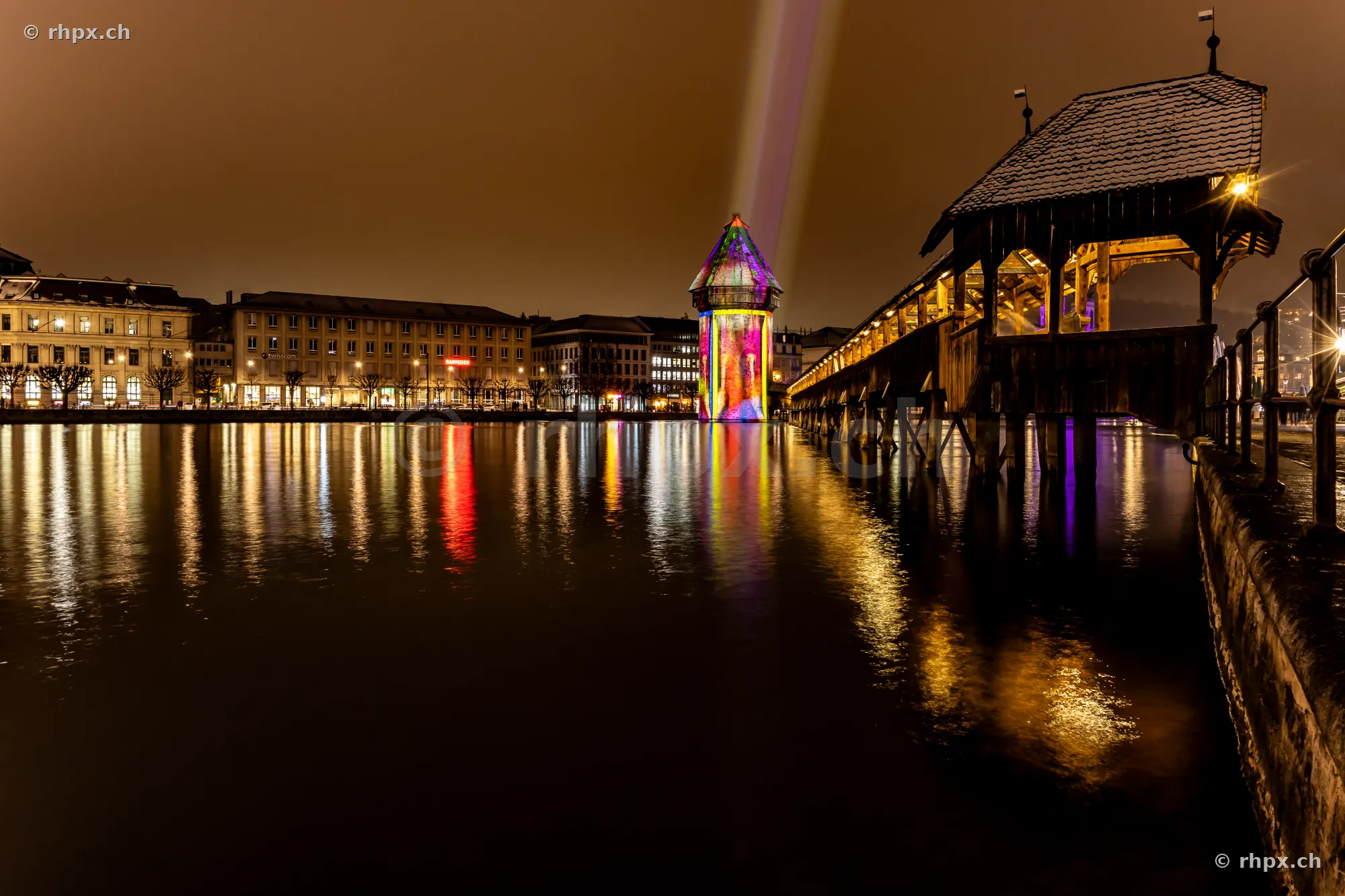 Der bunt beleuchtete Wasserturm der Kapellbrücke bei Nacht während des Lichtfestivals in Luzern