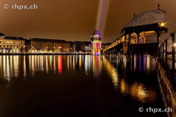 Der bunt beleuchtete Wasserturm der Kapellbrücke bei Nacht während des Lichtfestivals in Luzern
