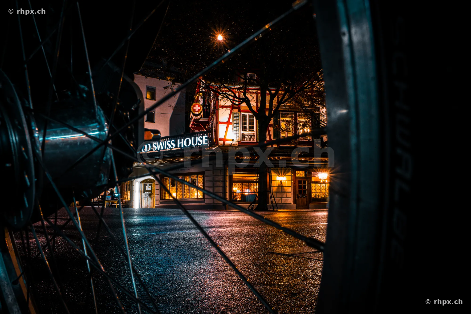 View through a bicycle wheel of the illuminated Swiss House in Lucerne at night