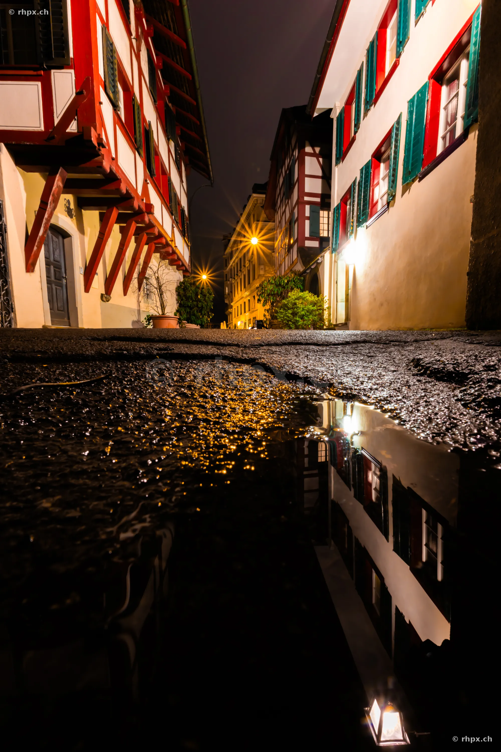 Reflection of half-timbered houses in a puddle at night in the old town of Lucerne