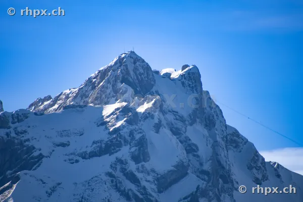 Schneebedeckter Gipfel des Berges Pilatus mit Hotel und Antennen unter blauem Himmel