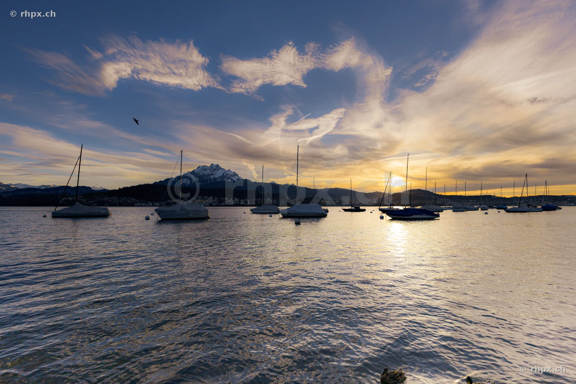 Sailboats on Lake Lucerne with Mount Pilatus in the background at sunset