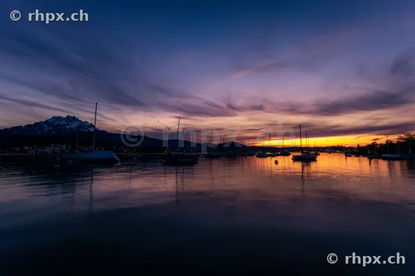 Silhouettes of sailboats on Lake Lucerne with Mount Pilatus at sunset