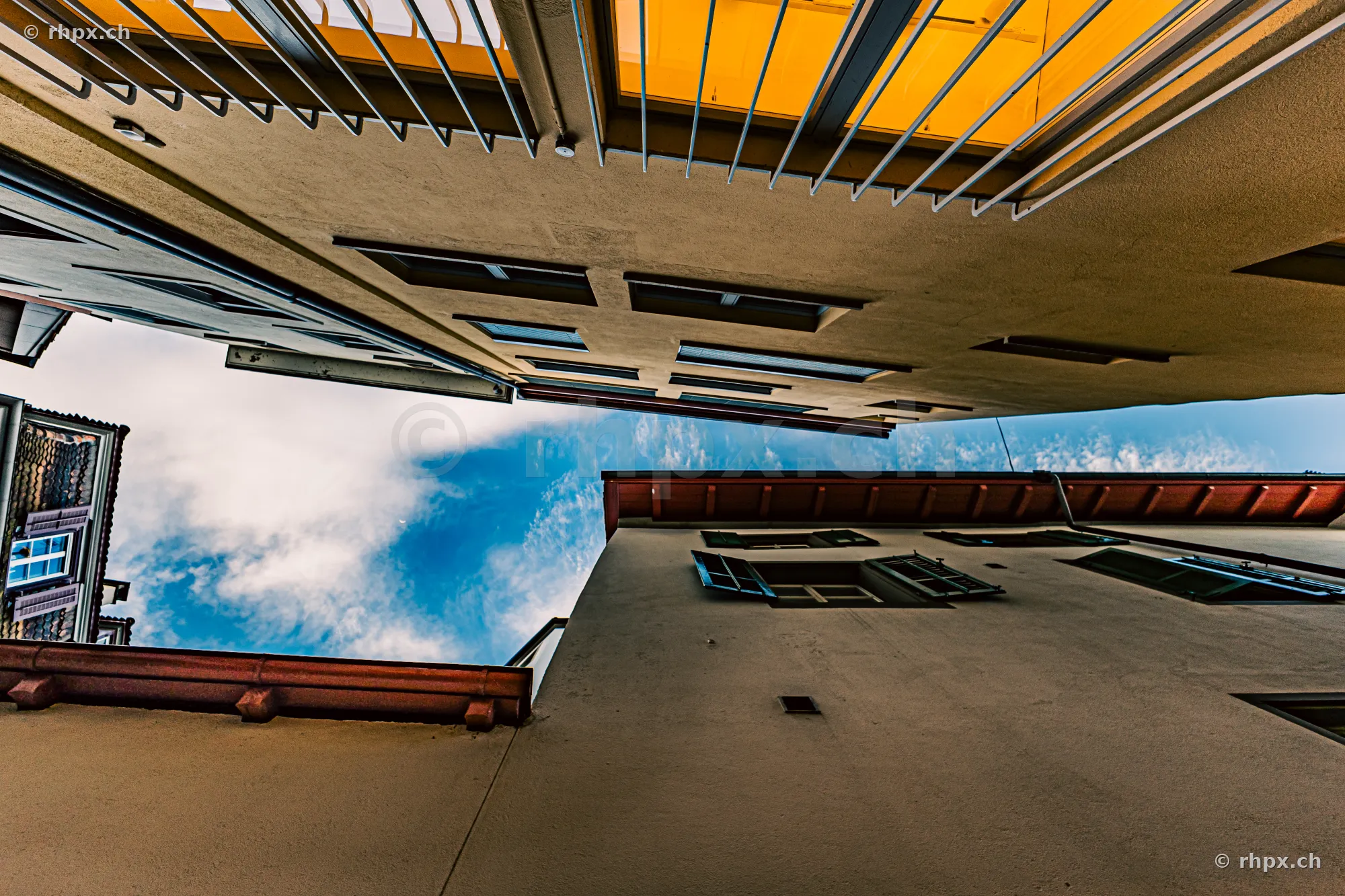 Blick nach oben durch eine enge Häuserschlucht in der Altstadt von Luzern mit sichtbarem blauem Himmel.