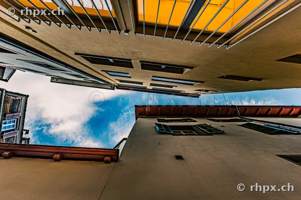 Looking up through a narrow urban canyon in the old town of Lucerne with visible blue sky.