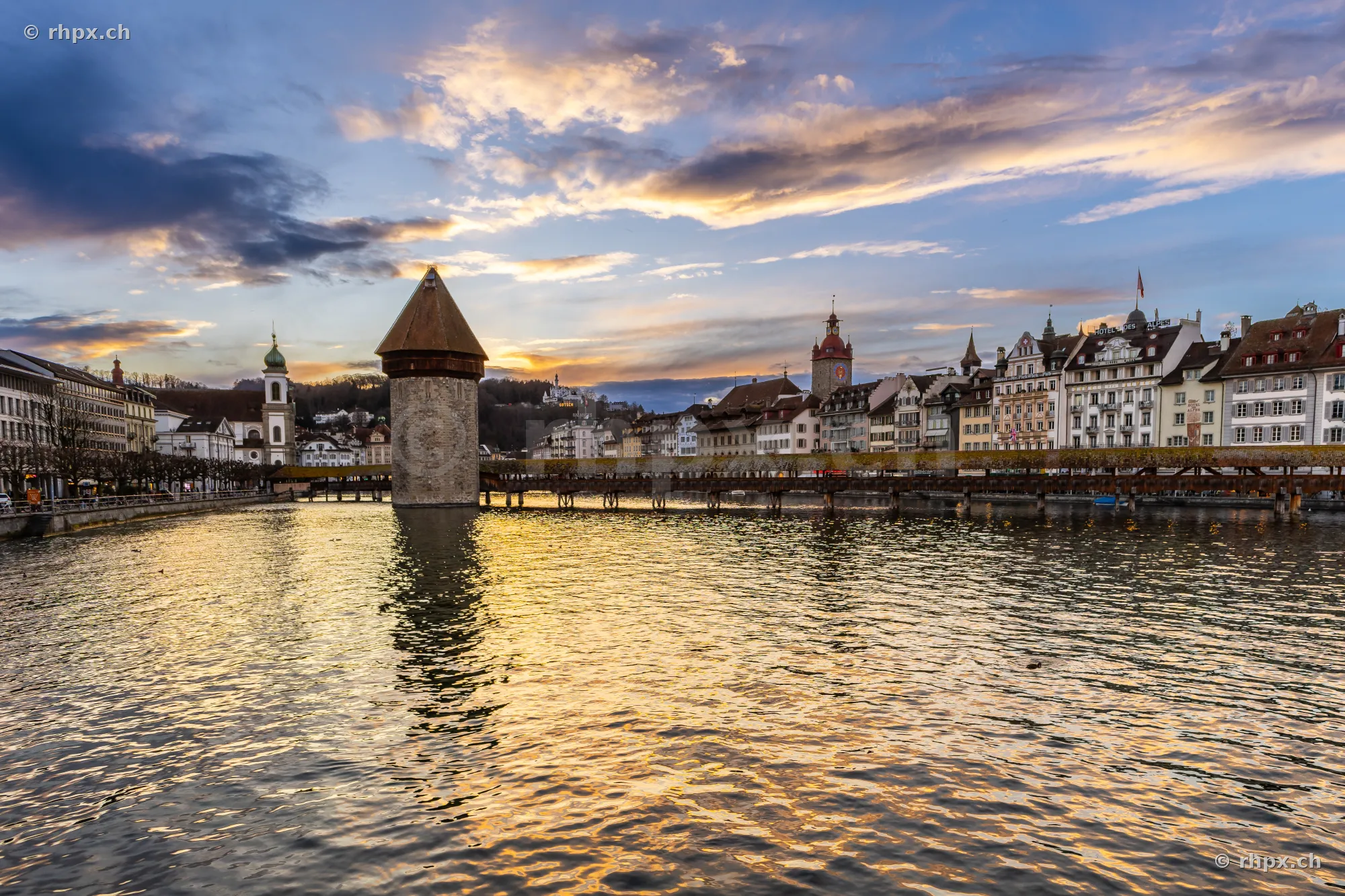 View of the Chapel Bridge and the old town of Lucerne over the Reuss river at sunset.
