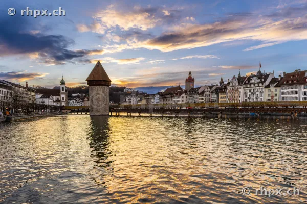 View of the Chapel Bridge and the old town of Lucerne over the Reuss river at sunset.