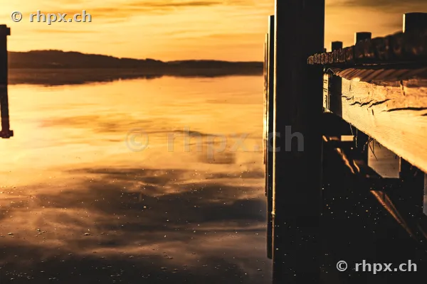 Blick von einem Holzsteg über den Sempachersee bei Sonnenuntergang