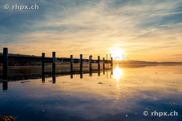 Ein langer Steg im ruhigen Sempachersee bei Sonnenuntergang