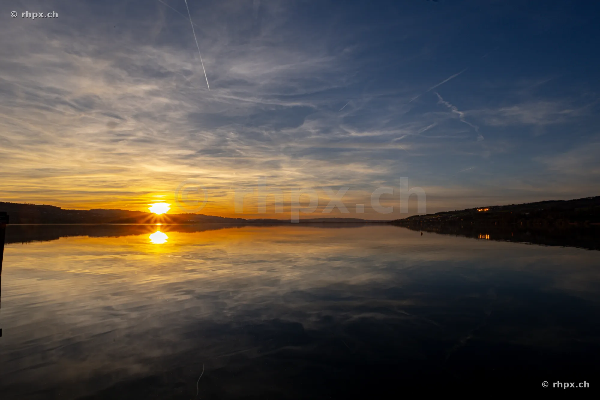 Sonne tief über dem ruhigen Sempachersee bei Dämmerung