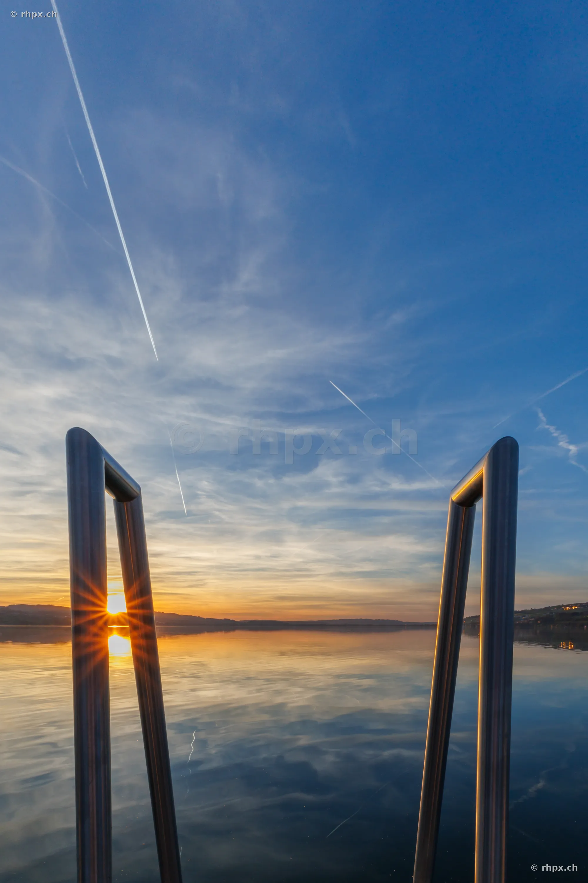 Blick durch eine Badeleiter auf den Sempachersee bei Sonnenuntergang