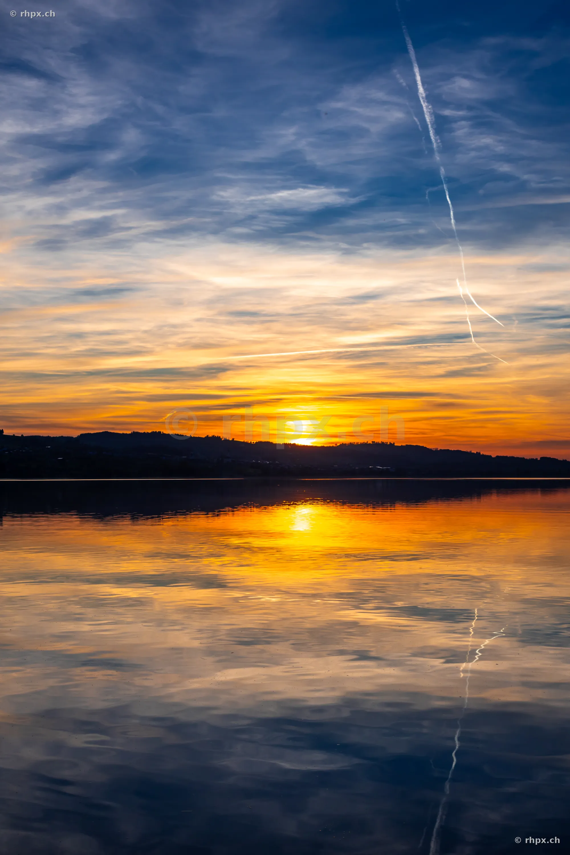 Blick auf den Sempachersee bei Sonnenuntergang mit reflektierendem Licht im Wasser