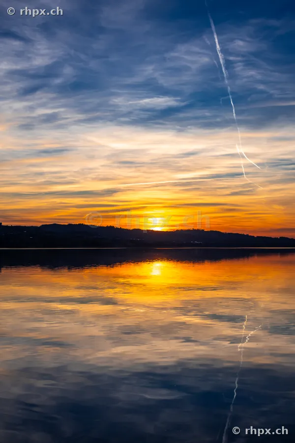 Blick auf den Sempachersee bei Sonnenuntergang mit reflektierendem Licht im Wasser