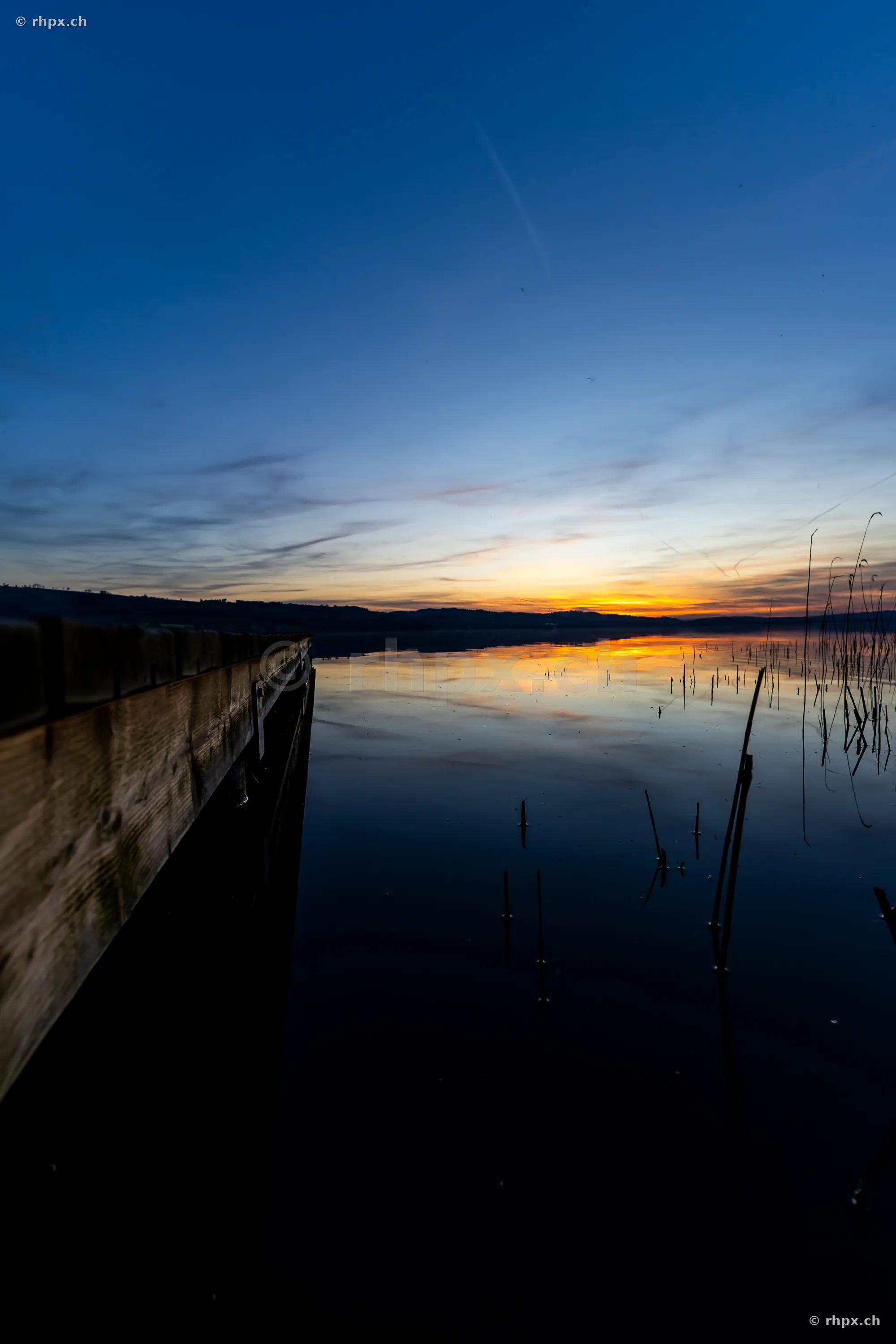 Blick auf einen Holzsteg am Sempachersee in der Abenddämmerung