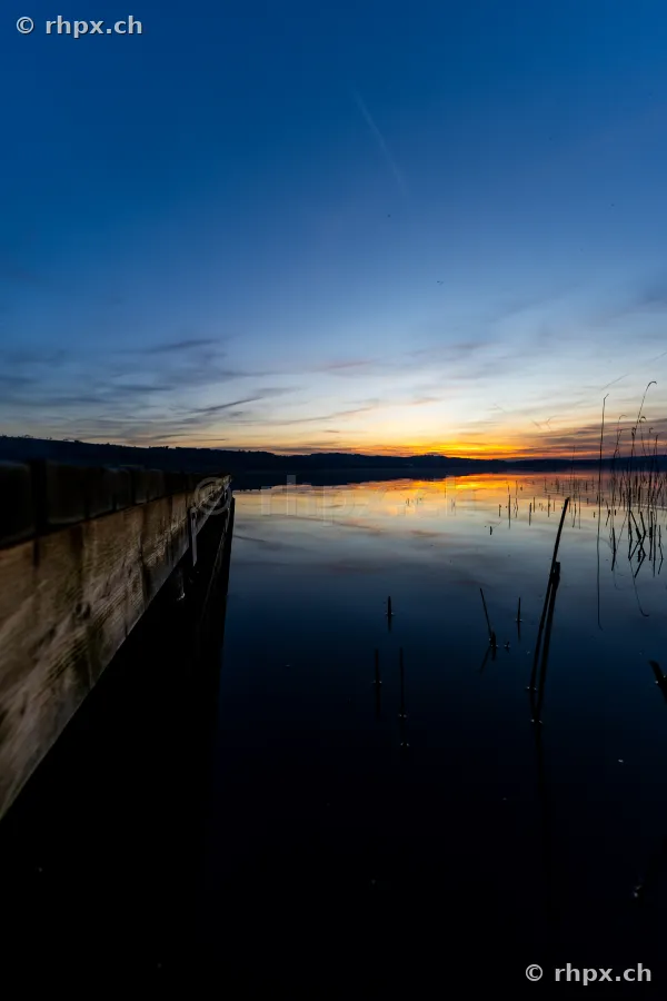 Blick auf einen Holzsteg am Sempachersee in der Abenddämmerung