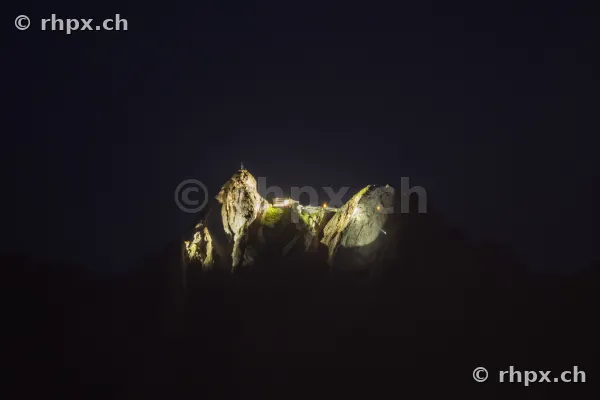 Der beleuchtete Gipfel des Berges Pilatus in der Nacht vor einem dunklen Himmel.