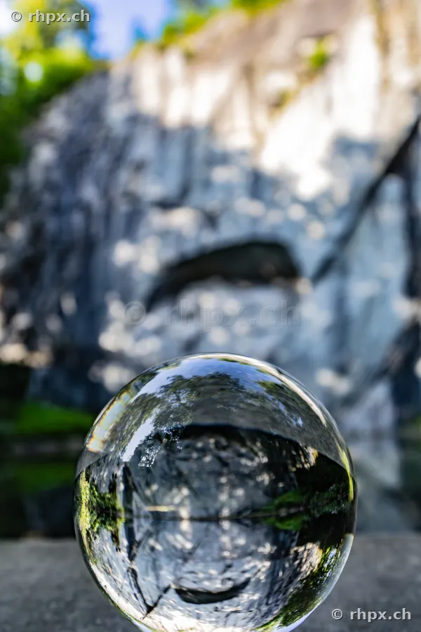Glass sphere placed in front of a vertical, shaded rock face