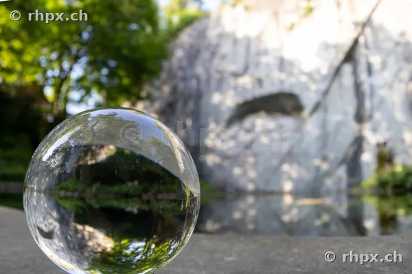 Glass sphere in foreground reflecting the Lion Monument in Lucerne