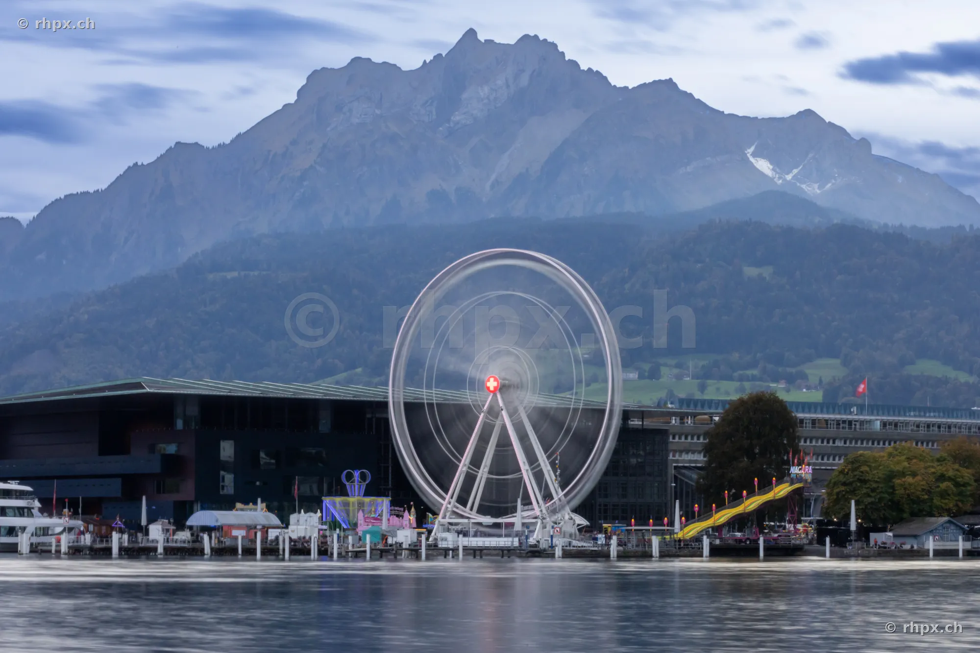 Ferris wheel at the boat landing stage in front of the KKL in Lucerne with Mount Pilatus in the background