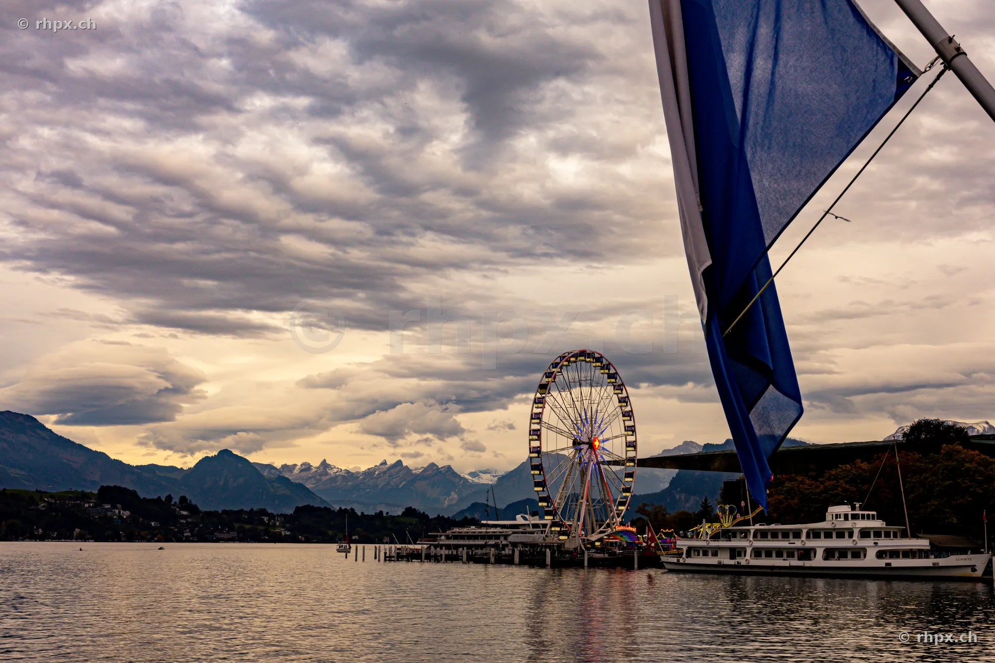 Ferris wheel and a boat at Lake Lucerne with a mountain backdrop