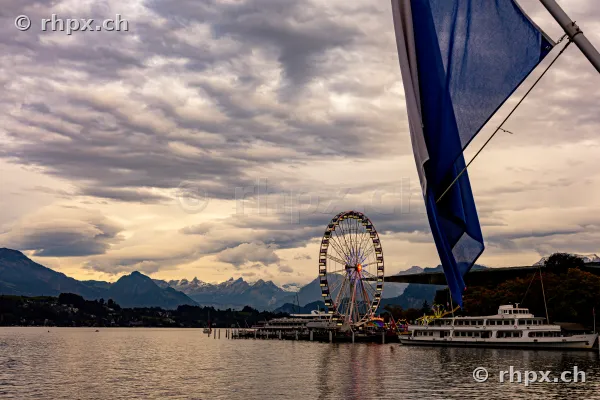 Ferris wheel and a boat at Lake Lucerne with a mountain backdrop