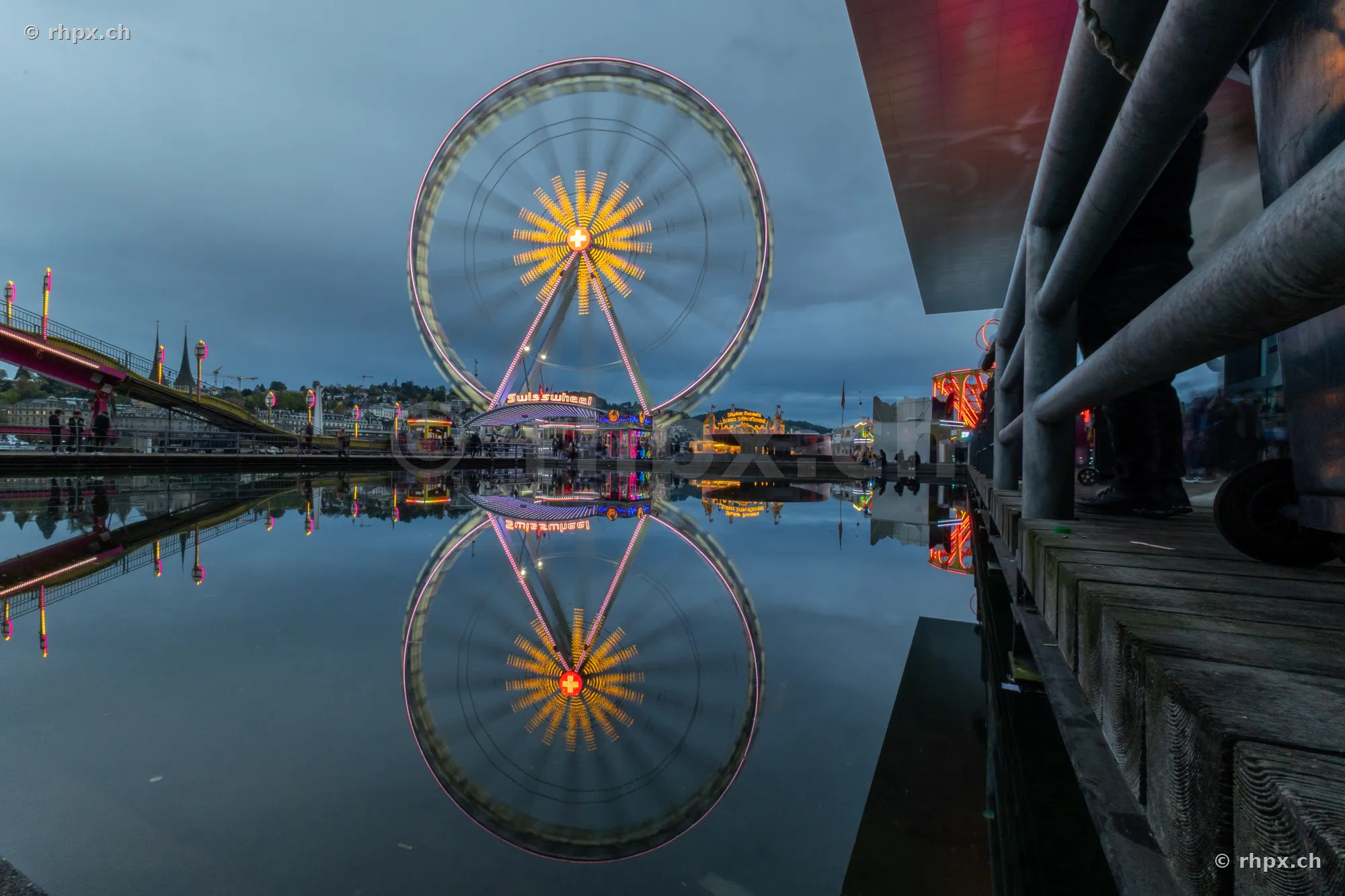 Ferris wheel with reflection in the water at the Lucerne lake basin during twilight