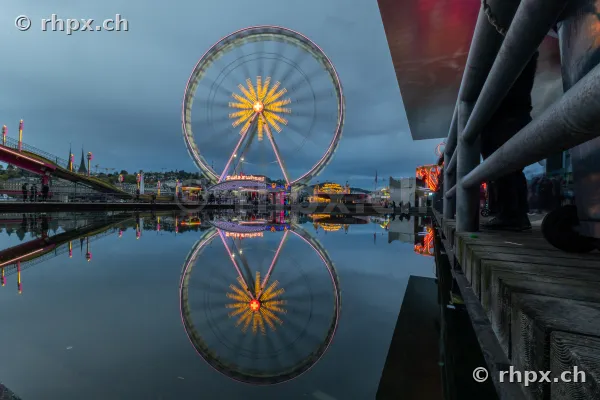 Riesenrad mit Spiegelung im Wasser am Luzerner Seebecken während der Dämmerung