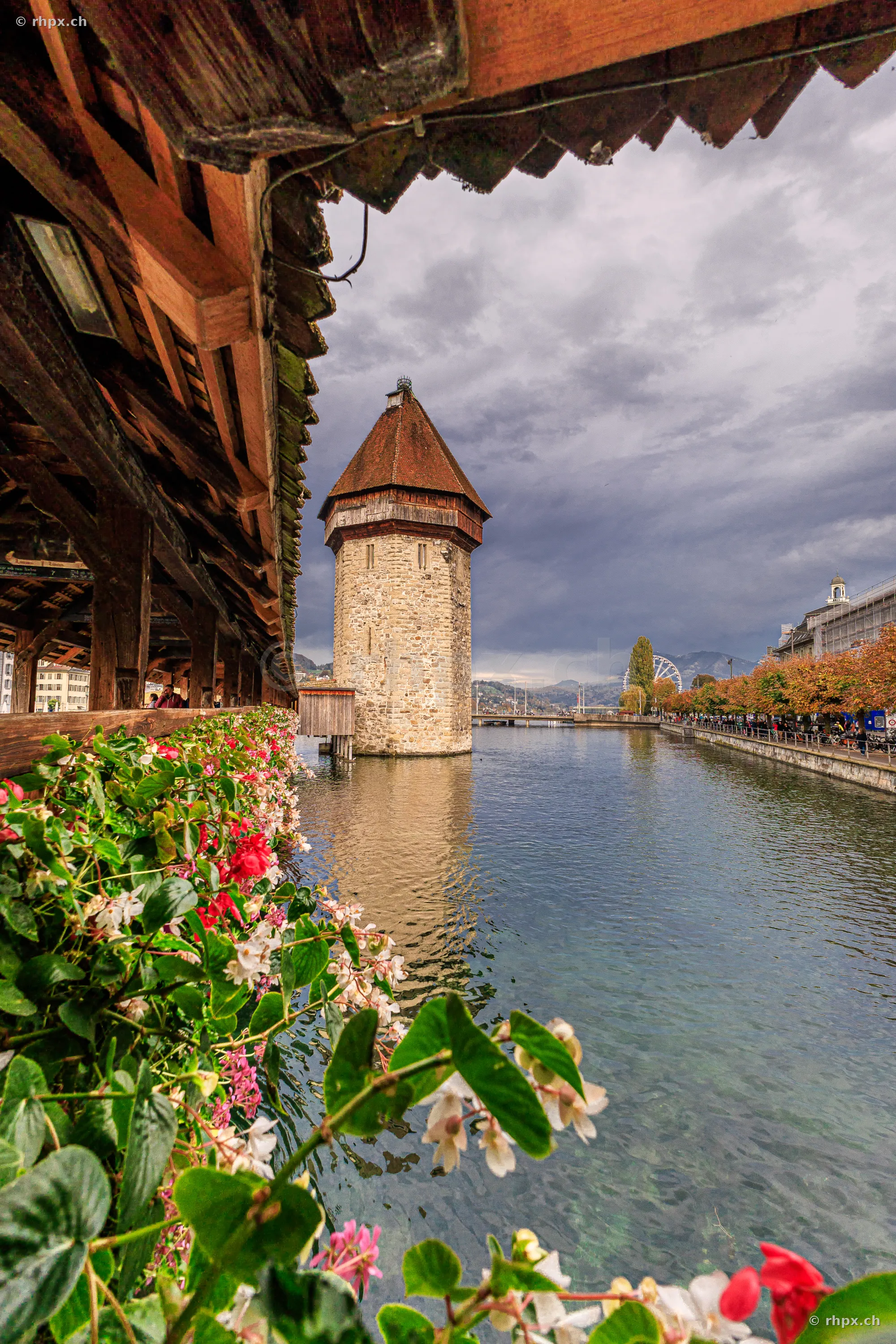 Blick durch das Innere der Kapellbrücke auf den Wasserturm in Luzern bei bewölktem Himmel.
