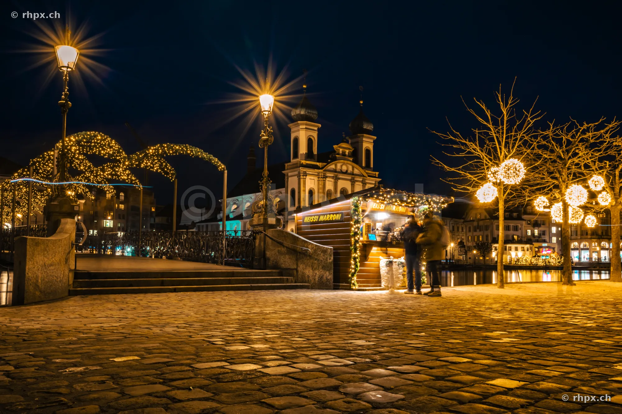 Night scene with illuminated chestnut stand in front of the Jesuit Church in Lucerne during the Christmas season