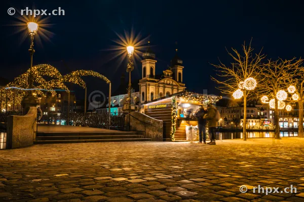 Nächtliche Szene mit beleuchtetem Marronistand vor der Jesuitenkirche in Luzern zur Weihnachtszeit