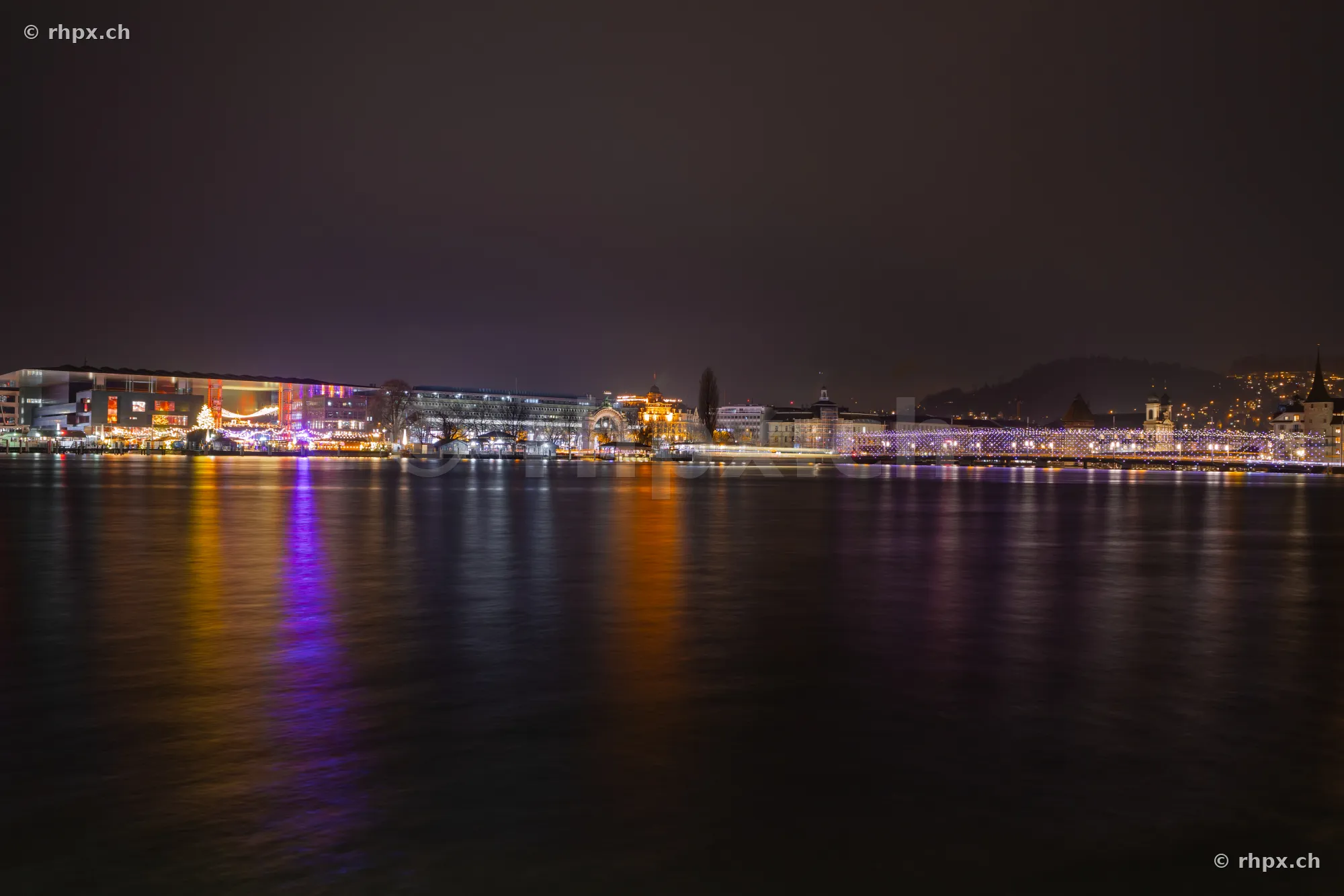 Night view of the Christmas-lit lake basin in Lucerne with reflections in the water.