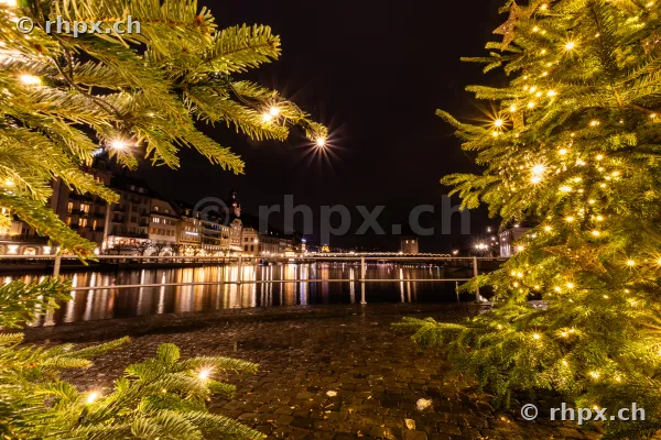 View through illuminated Christmas trees of the city of Lucerne at night on the Reuss river