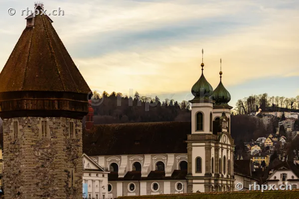 Water tower of the Chapel Bridge and Jesuit Church in the old town of Lucerne under a cloudy sky