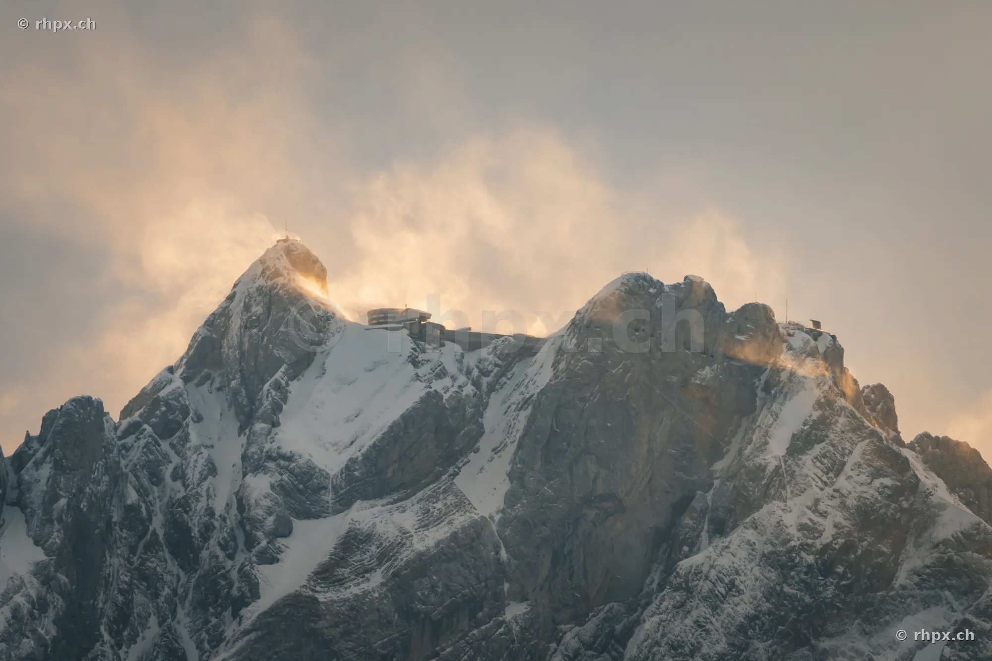 Snow-covered peak of Mount Pilatus with hotel and mountain station in evening light.