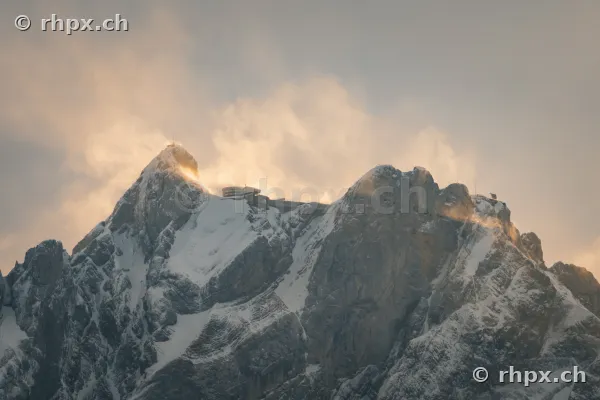 Verschneiter Gipfel des Pilatus mit Hotel und Bergstation im Abendlicht.